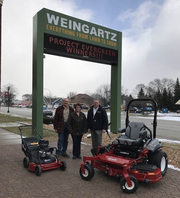 Joe and Barb Matney (left) of In Memory of Community Garden and the Warrendale Community Organization, and Dan Pagel of Exmark dealer Weingartz Utica, stand next to the mowers that will help maintain green spaces in the Detroit community.